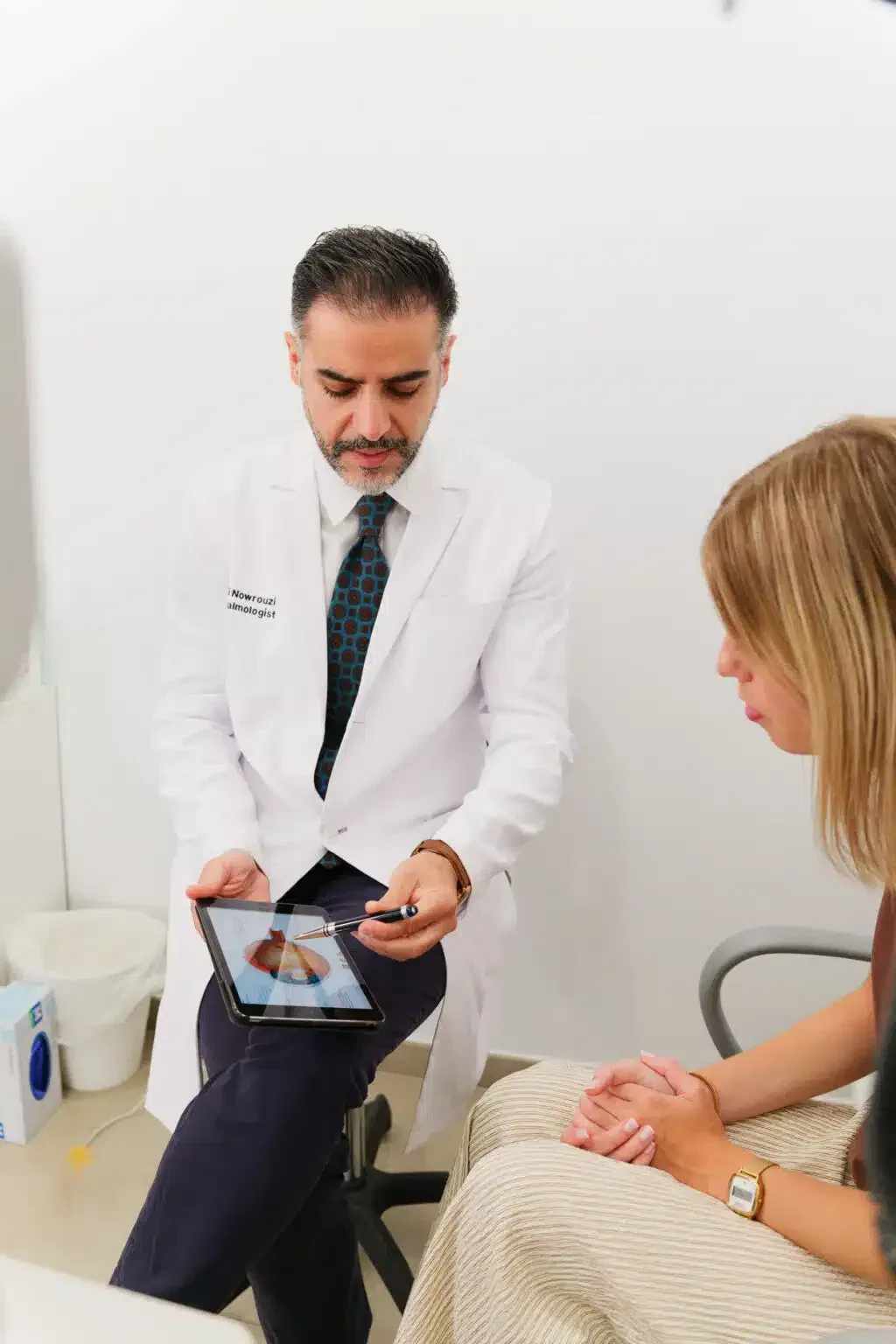 Médico en consulta mostrando información en una tablet a una paciente en una clínica.